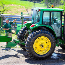 Load image into Gallery viewer, man using hose to clean tractor
