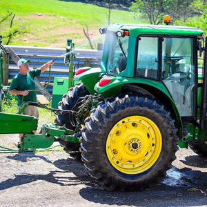 Man using hose to clean his tractor
